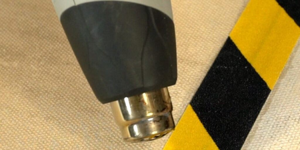 Heat Gun Blasting on Yellow and Black Hazard Non-Slip Tape to Remove it