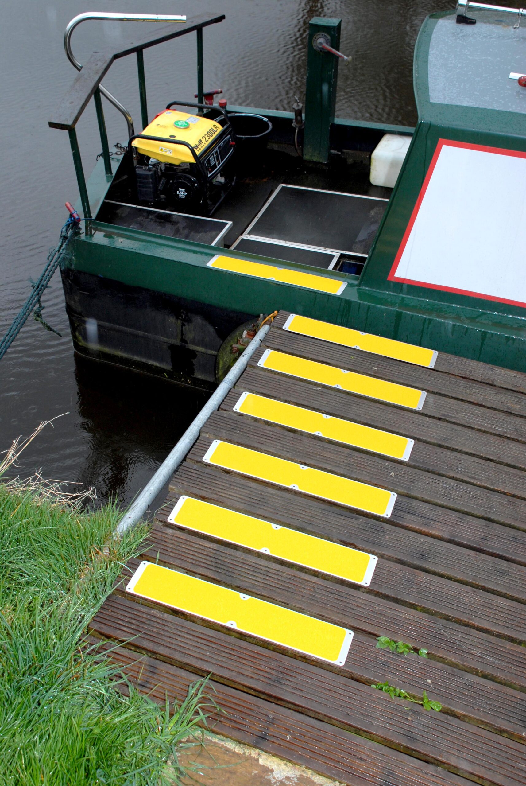 Yellow bolt down plates on decking that lead to a boat.